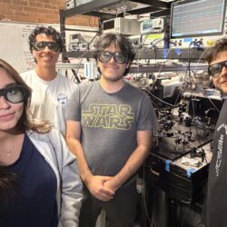 Four students with goggles standing in a lab