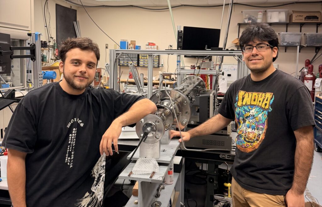 Two students standing in a lab surrounded by equipment