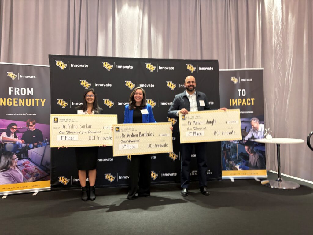 UCF postdoctoral fellows Pritha Sarkar, Andrea Bardales, and Mahdi Eshaghi hold up giant checks after competing in Knight Pitches competition.